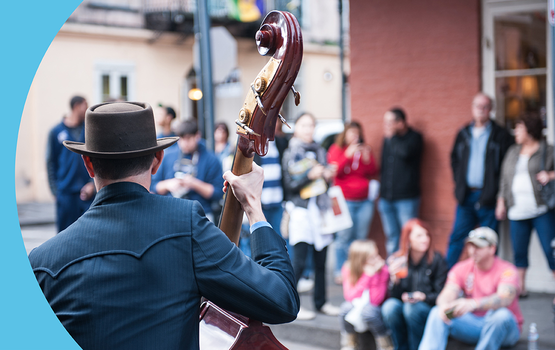 A guy playing an instrument in the streets of New Orleans with people watching and listening.