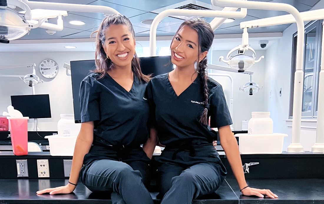Smiling Nanji twins sitting on a lab table