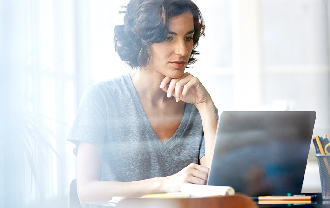 Woman sitting at a desk looking at her laptop