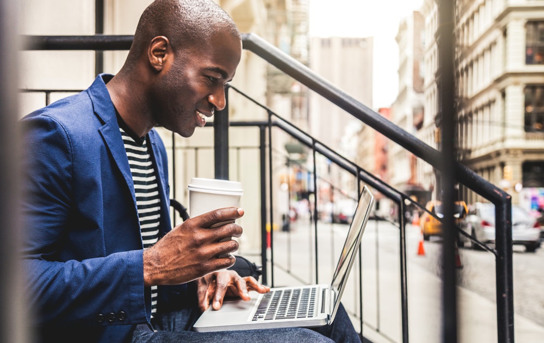 Man on laptop sitting outside on steps