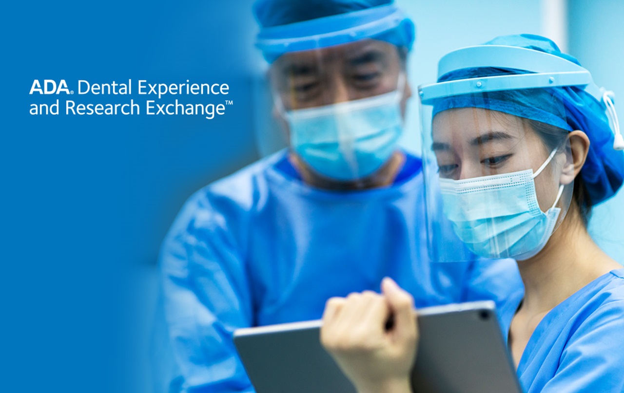 Dentists in a sterile environment in full PPE working on a tablet.