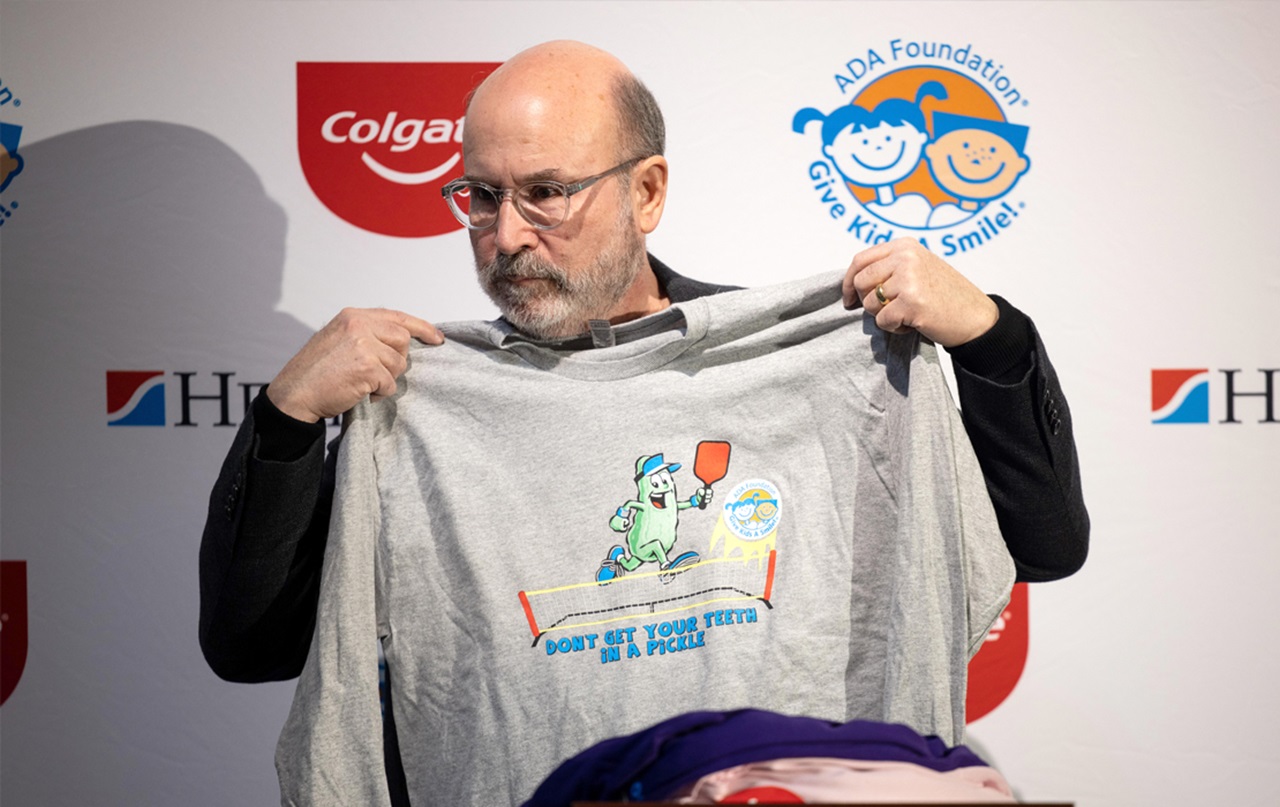 Innovator: Jeff Dalin, D.D.S., the co-founder of the Give Kids A Smile program, displays the T-shirt design for the 2023 volunteers.