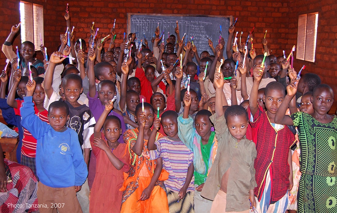 A room full of kids holding toothbrushes from volunteer event in Tanzania