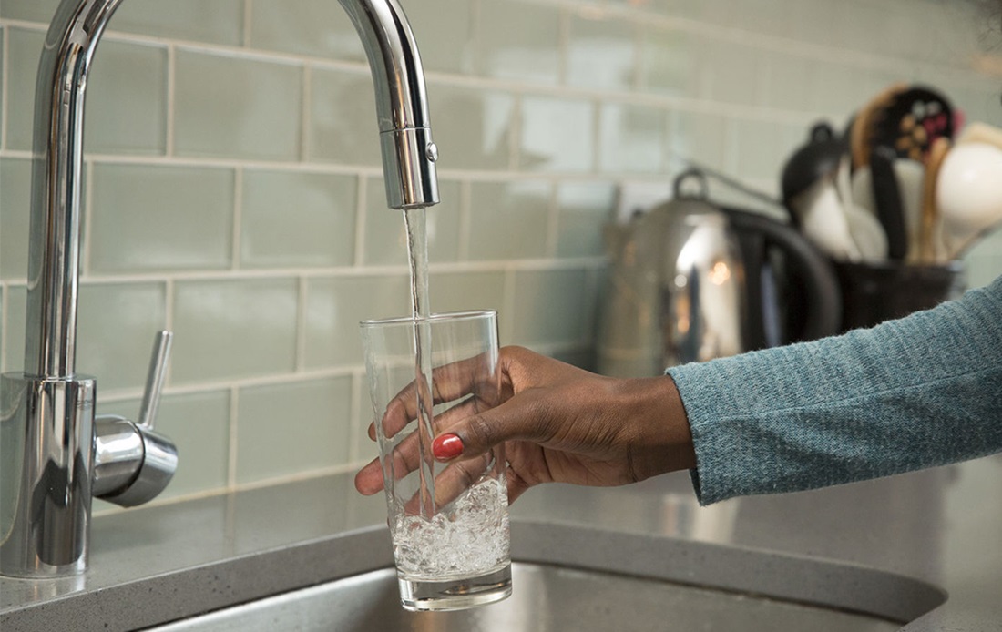 An image of a person filling up a glass of water.