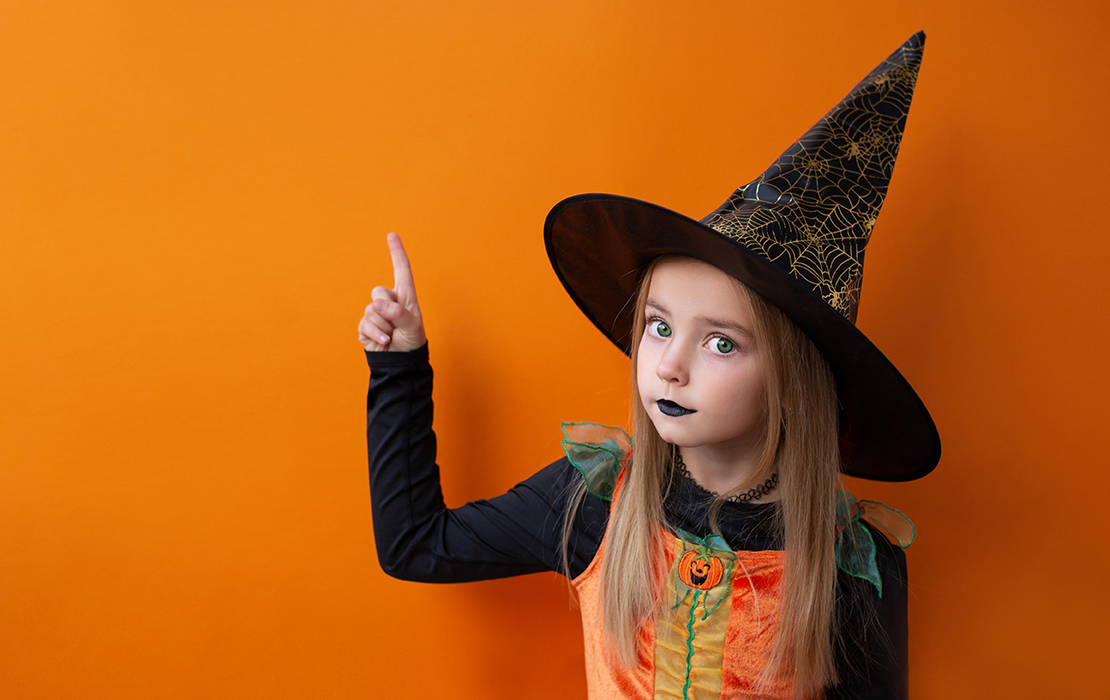 Girl dressed as witch pointing finger up