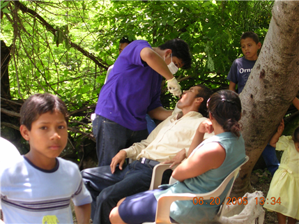 dentist treating patients in outdoor clinic while kids look on