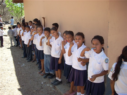 children lined up outside brushing teeth