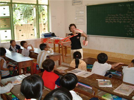 Women in classroom with large mouth model demonstrating brushing