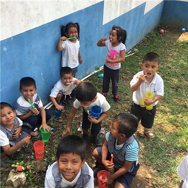 Children outside clinic brushing teeth