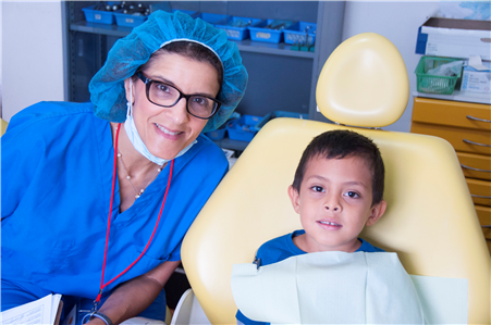 dentist posing with young boy in chair