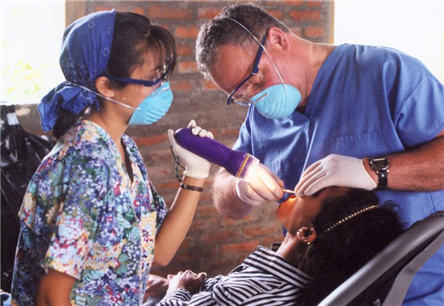 two dentists treating patient using flashlight
