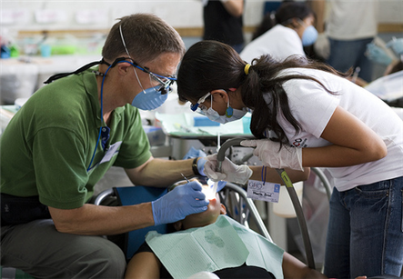 Two dentists leaning over patient lying in chair