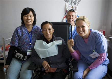 Patient sitting in chair with dentists on her sides