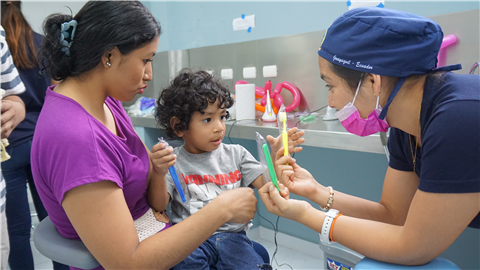 Volunteer Showing toothbrushes to child