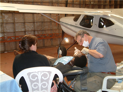 Photo of patient receiving oral health care with a small airplane in the background