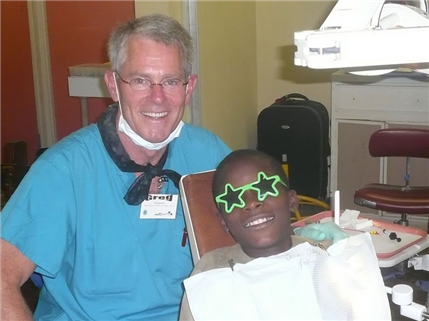 Dentist with Jamaican patient who has star sunglasses on 