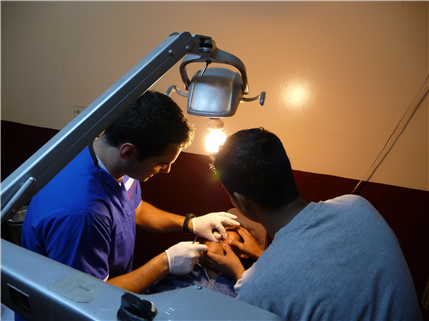 Two dentists treating patient under light