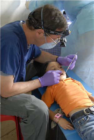 Dentist treating small boy in orange shirt