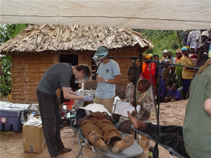 Man on outside treatment table with mud hut in background