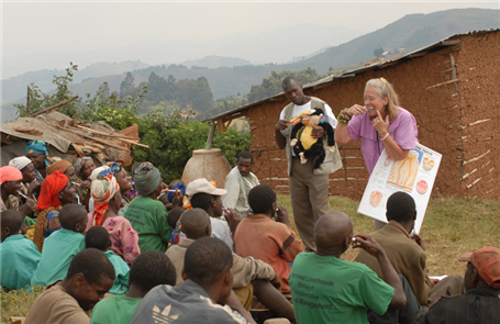 Woman and Man teaching oral health education in front of mud hut