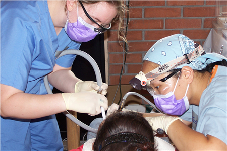 Photo of two dental volunteers providing care in a clinic