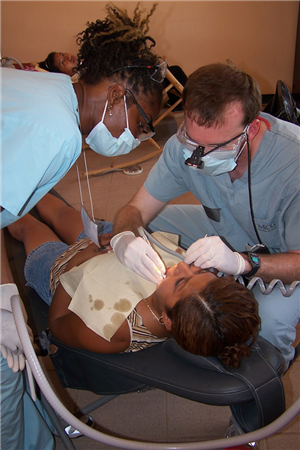 Photo of two volunteers providing care to a woman in a dental chair