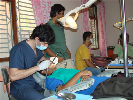 Photo of clinic with close-up of a dental volunteer providing care