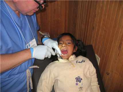 Photo of dental volunteer examining a child's mouth
