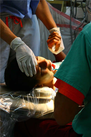 Close up photo of a patient receiving dental care at a clinic while holding a caregiver's hand