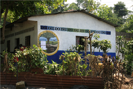 Photo of the exterior of a white and blue building in a tropical setting