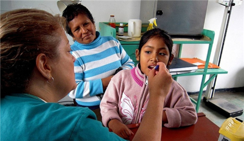 Photo of dental clinic with a child receiving care while an adult looks on
