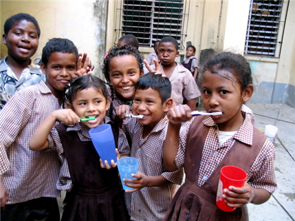 Photo of ten children, three of whom are brushing their teeth