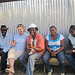 Photo of five adults sitting against a corrugated metal wall