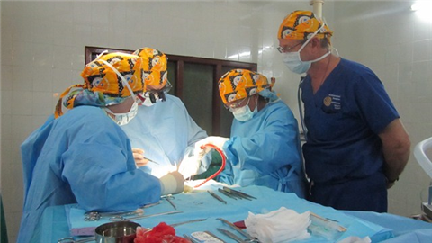 Photo of a dental team in yellow head scarves treating a patient