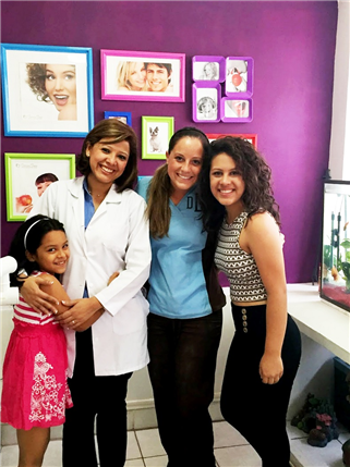 Three women and a girl pose in front of a purple wall