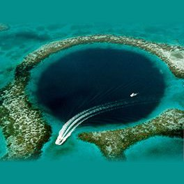 Photo of boat sailing over deep sinkhole surrounded by reefs in the ocean