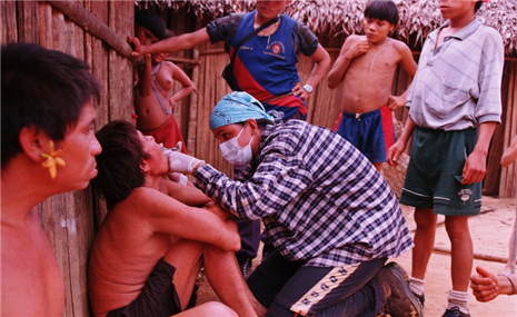 Photo of dental volunteer examingin a person outside of a hut