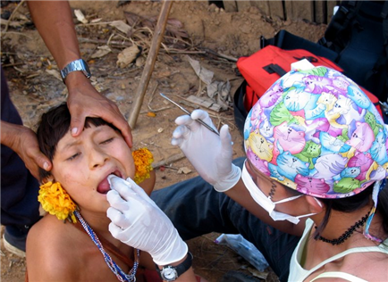 Photo of dental volunteer providing care to a person wearing beads and flowers