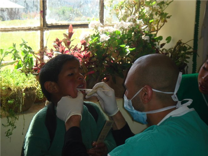 Photo of person providing dental care to a child in a lush setting