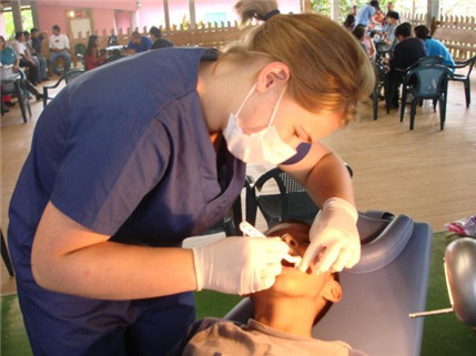 Photo of a dental care provider providing oral health care to a young boy