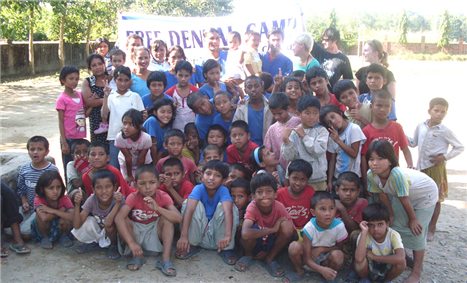 Photo of a large group of kids and adults in front of a VOLNEPAL banner