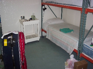 Photo of a small room with a cot and a suitcase
