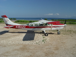 Photo of an airplane on packed soil with water in the background