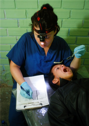Photo of dental volunteer marking a chart while examining a child